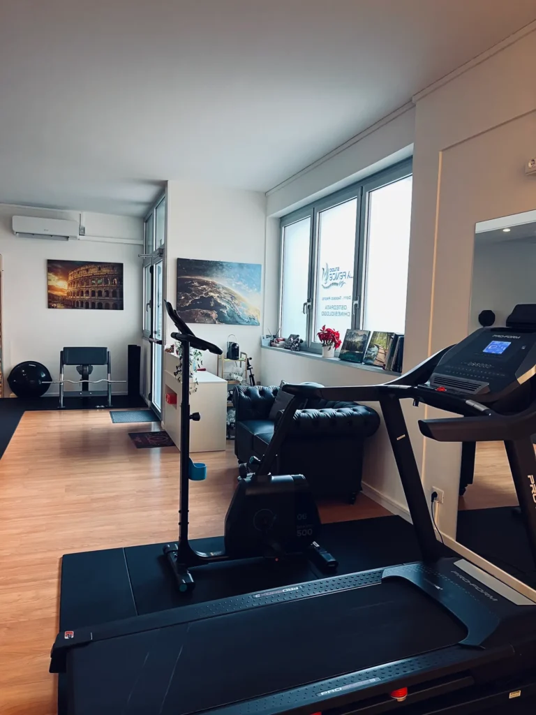 Area cardio con tapis roulant, cyclette e divano in pelle presso lo studio a Udine